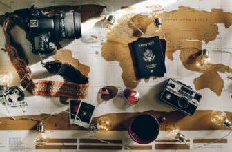 A collection of essential travel gear including a backpack, packing cubes, a travel pillow, and a water bottle arranged on a wooden surface.