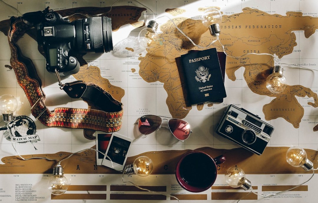 A collection of essential travel gear including a backpack, packing cubes, a travel pillow, and a water bottle arranged on a wooden surface.