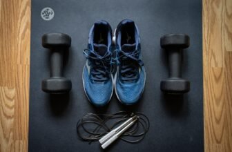 A collection of simple fitness accessories like resistance bands, foam rollers, and posture correctors arranged on a wooden floor.